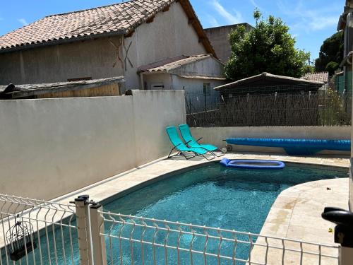 une piscine avec une chaise bleue dans un jardin dans l'établissement Maison de vacances - St Joseph, à Beaucaire