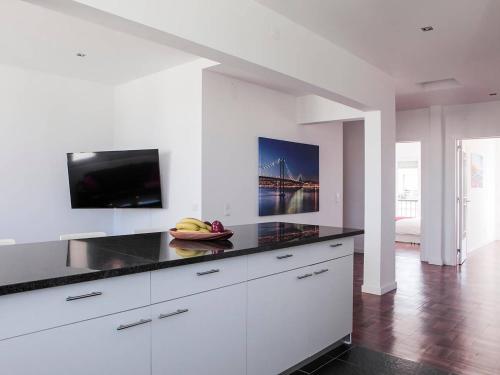 a kitchen with white cabinets and a flat screen tv at casaRene in Carcavelos