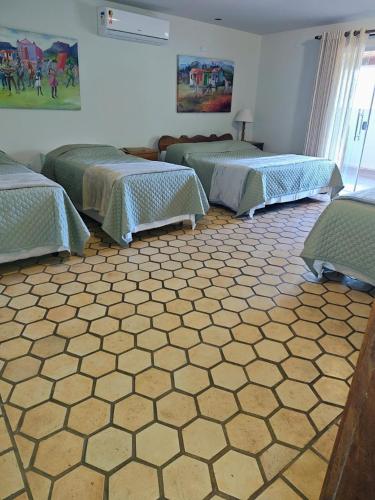 a room with three beds and a tile floor at Lendas do Capão Pousada in Vale do Capao