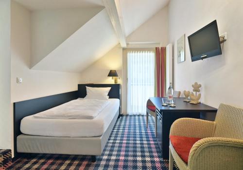 a hotel room with a bed and a desk at Landhaushotel Hof Wasserkuppe in Poppenhausen