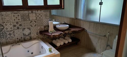 a bathroom with a tub and a sink and a mirror at Lendas do Capão Pousada in Vale do Capao