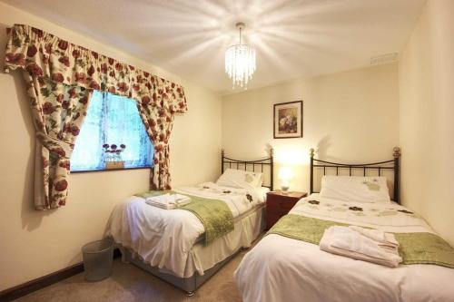 two twin beds in a bedroom with a window at Carriage House in Barnstaple