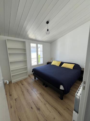 - une chambre avec un lit, des murs blancs et du parquet dans l'établissement Charmante maison de Gros-Jonc, au Bois-Plage-en-Ré