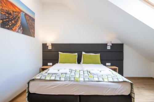a bedroom with a bed with green pillows at Anna Vendégház in Visegrád