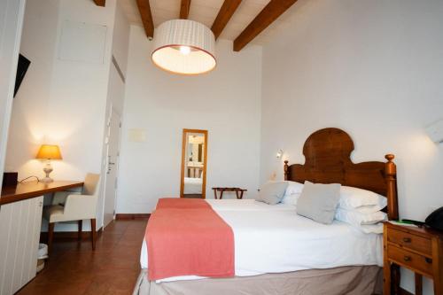 a bedroom with a large white bed and a desk at Hotel Rural Binigaus Vell in Es Migjorn Gran
