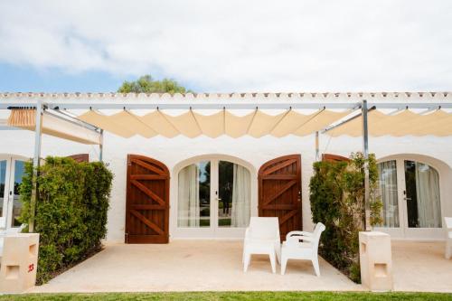 a wedding venue with wooden doors and white chairs at Hotel Rural Binigaus Vell in Es Migjorn Gran