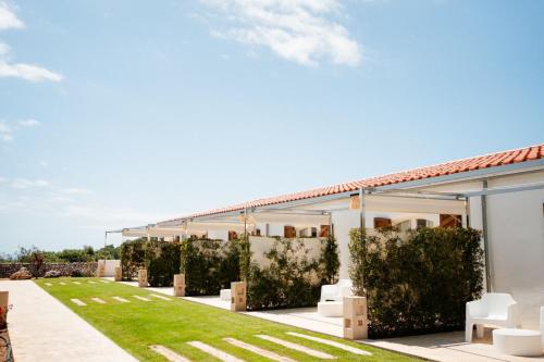 a garden with white chairs and a building at Hotel Rural Binigaus Vell in Es Migjorn Gran
