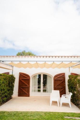 two white chairs sitting in front of a house at Hotel Rural Binigaus Vell in Es Migjorn Gran