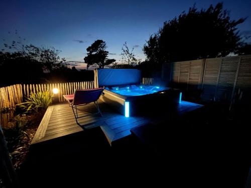une cour arrière avec un bain à remous et une chaise sur une terrasse dans l'établissement La cabane des plages, à Plouescat