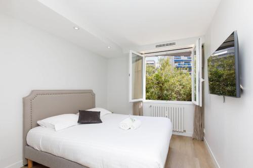 une chambre avec un lit blanc et une fenêtre dans l'établissement CROISETTE MARTINEZ - Luxueux T3 70m2 et balcon, à Cannes