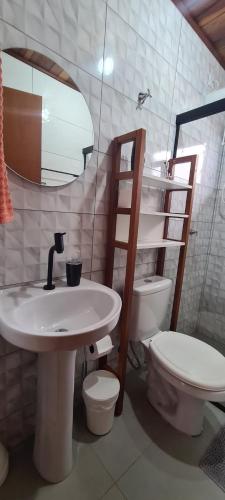 a bathroom with a sink and a toilet and a mirror at Casa aconchego perto da praia in Guaratuba