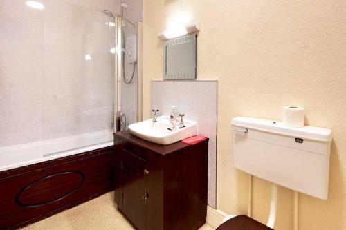 Un baño con lavabo, inodoro y ducha. en Tracy, en Barnstaple