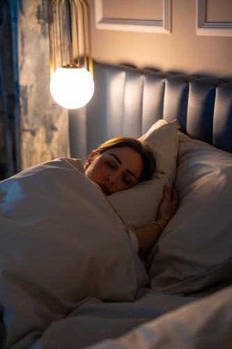 a woman laying in bed with a pillow at VILLA MADRE Suites e Private Spa in Grottaferrata