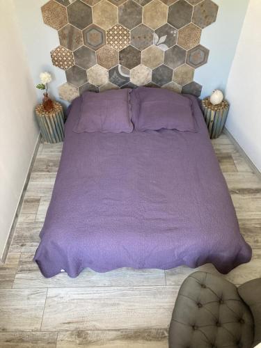 - un lit avec une couverture violette sur du parquet dans l'établissement Le studio D'auguste- Cœur de Nîmes-chaleureux-emplacement idéal, à Nîmes