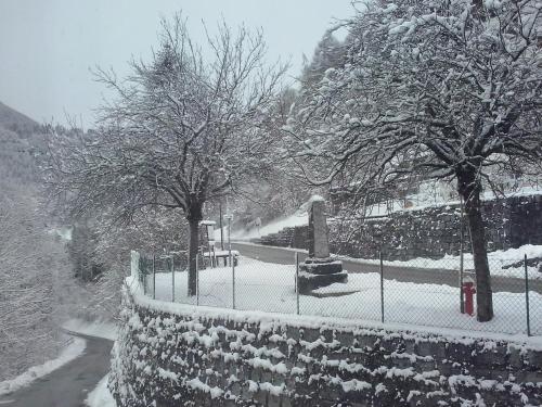 a snow covered park with trees and a fence at Albergo Bellavista in Castello Tesino