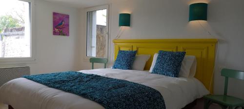 - une chambre avec un lit doté d'une tête de lit jaune et d'oreillers bleus dans l'établissement Retour de plage, à Regnéville-sur-Mer