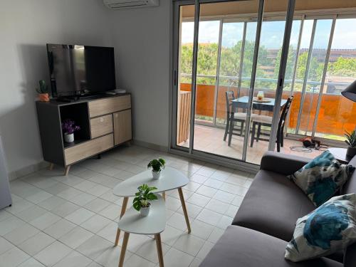 un salon avec un canapé, une télévision et une table dans l'établissement Studio Fréjus Plage l Clim l WiFi l Parking privé, à Fréjus