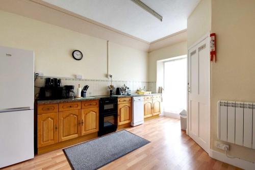 una cocina con armarios de madera y un reloj en la pared en Fortescue, en Barnstaple