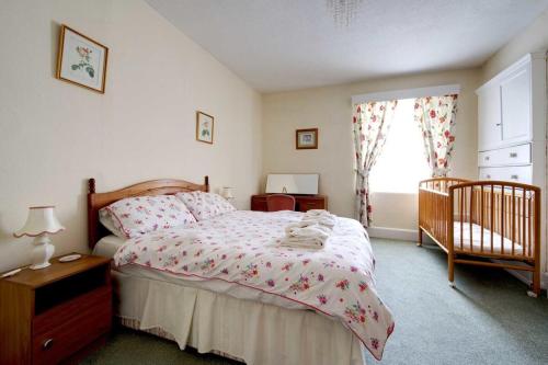 Un dormitorio con una cama con cuna y una ventana. en Fortescue, en Barnstaple