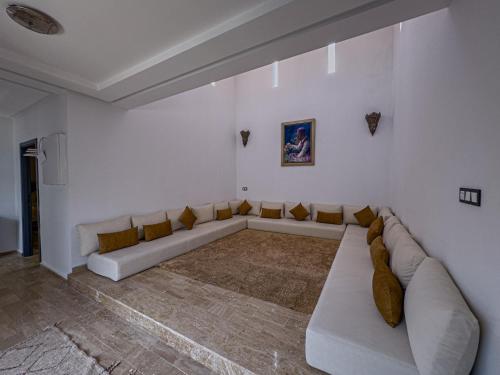 a white living room with a long couch in it at Riad Tonaroz Gold in Marrakech