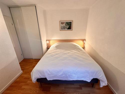 Cette petite chambre comprend un lit avec des draps blancs. dans l'établissement magnifique T2 vue sur parc, à Capbreton