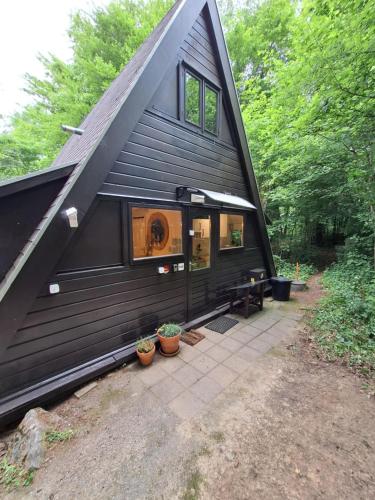 a black house with a dog looking out the window at Chalet Séquoia 138 Nature, piscine et chien bienvenu à Durbuy in Durbuy