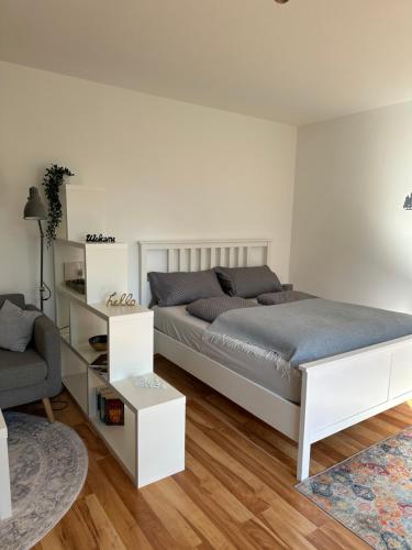 a white bedroom with a bed and a chair at Cozy City Apartment Penzberg in Penzberg