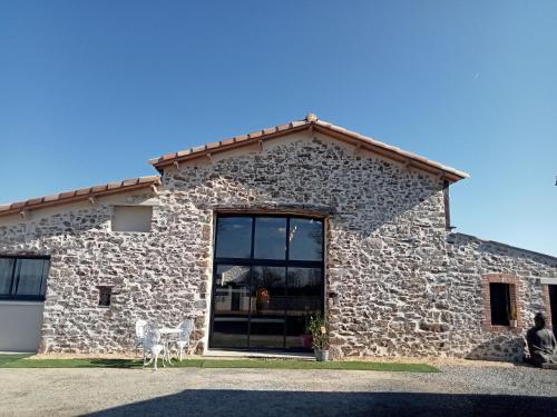un edificio in pietra con una grande finestra di Chambres d'hôtes LA GRANGE DU PA de LA GROLLE a Rocheservière