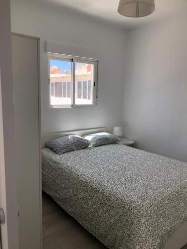 a white bedroom with a bed and a window at Casa Yolanda in Tías