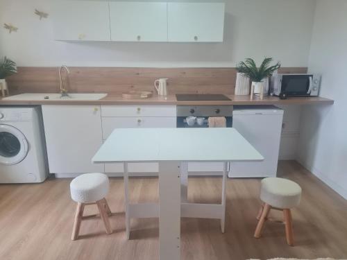 une cuisine avec une table blanche et deux tabourets dans l'établissement DISNEY LOVE - VAL D EUROPE - Vallée Village - VILLAGE NATURE - PARC ASTERIX, à Carnetin