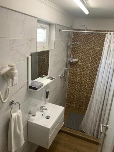 a white bathroom with a sink and a shower at Mamácska Apartmanok in Bogács