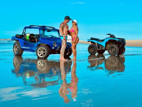 a man and woman standing on the beach with a wheeler at Tô em Casa Hospedagem 2 in Jijoca de Jericoacoara