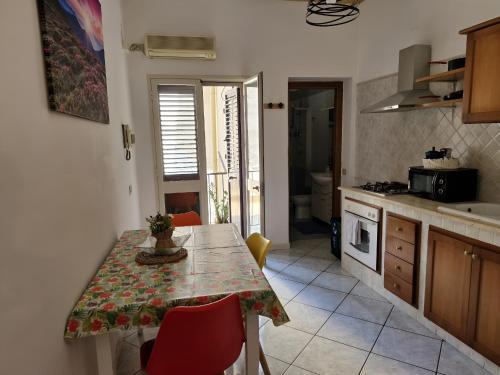 una cucina con tavolo e sedie e una cucina con lavandino di Happie Casa Stazione Centrale a Palermo