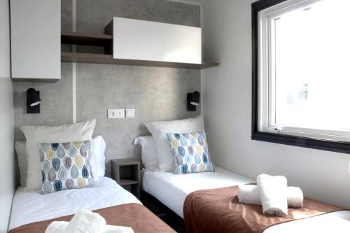 une chambre d'hôtel avec deux lits et une fenêtre dans l'établissement Réveillez la Belle au Bois Dormant - Bungalow moderne, confort & linge inclus, à Saint-Jean-de-Monts