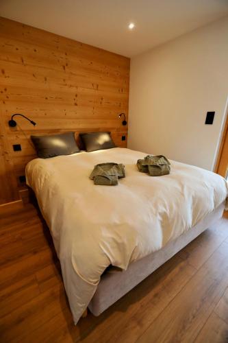 - une chambre avec un grand lit blanc et des murs en bois dans l'établissement Chalet des beauxmonts, à Morillon