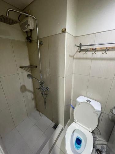a bathroom with a shower and a toilet with a blue seat at Shell Residences MOA by Kirstie in Manila