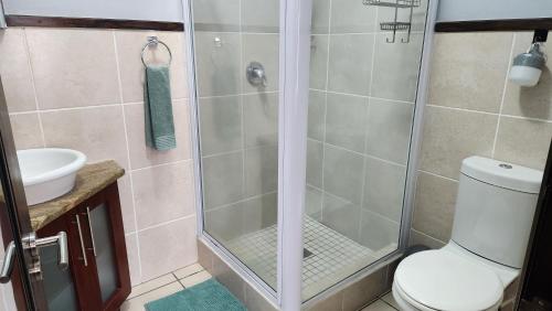 a bathroom with a shower with a toilet and a sink at Topanga 17 in Uvongo Beach