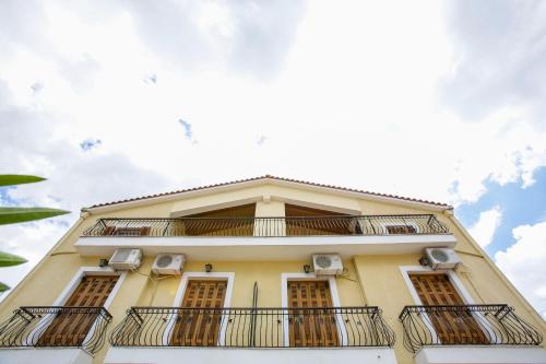 a tall yellow building with balconies on it at Papadatos Studios in Argostoli