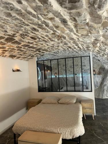- une chambre avec un lit et un plafond en pierre dans l'établissement Appartement avec jacuzzi, à Sisteron