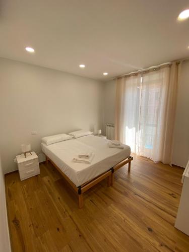 a white bedroom with a bed and a wooden floor at Begonia Apartment in Rome
