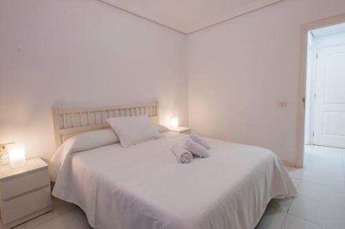 a white bedroom with a white bed with two pillows at Bungalow Golf del Sur in San Miguel de Abona
