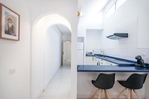 a kitchen with a blue counter and two black chairs at Bungalow Golf del Sur in San Miguel de Abona