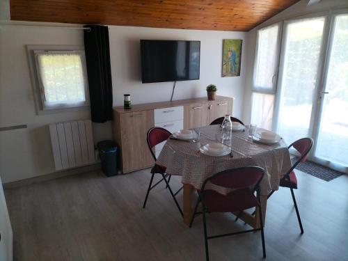 a dining room with a table with chairs and a television at Studio proche des thermes, des barthes, des plages et de Dax ! in Saubusse