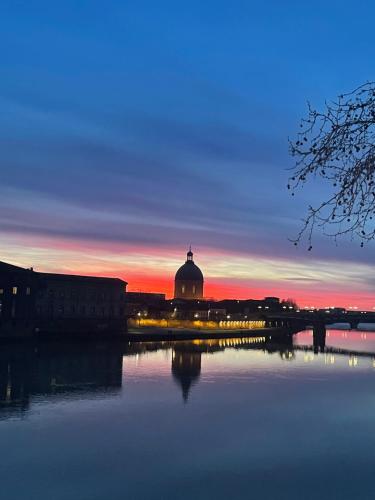 un coucher de soleil sur une ville avec un pont sur une rivière dans l'établissement Appartement place du Fer à Cheval, à Toulouse