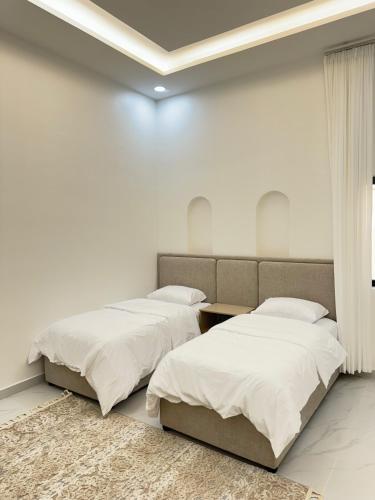 two beds in a room with white walls at Lateen Chalet - شاليه لتين in Nizwa