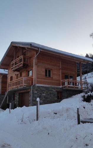 une cabane en rondins avec de la neige devant elle dans l'établissement Chalet neuf Virage 12 , Tour de France 1st line, à La Plagne Tarentaise