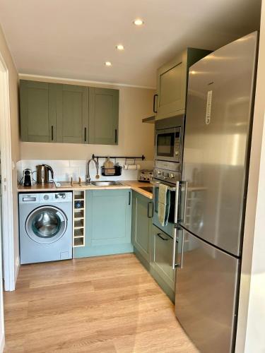 a kitchen with green cabinets and a stainless steel refrigerator at guest house aux portes de Deauville in Bonneville-sur-Touques