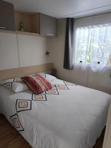 une chambre avec un grand lit blanc avec une fenêtre dans l'établissement Mobil home haut de gamme île d'Oléron à 100m de l'océan, à Saint-Denis-dʼOléron