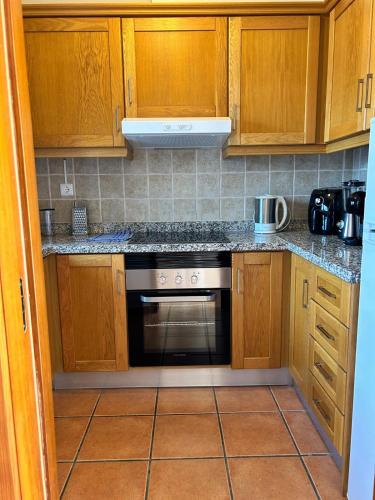 a kitchen with wooden cabinets and a stove top oven at Alqueva - Casa Da Luz in Mourão