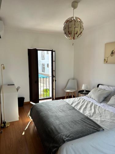 a bedroom with a bed and a window and a chandelier at Alqueva - Casa Da Luz in Mourão
